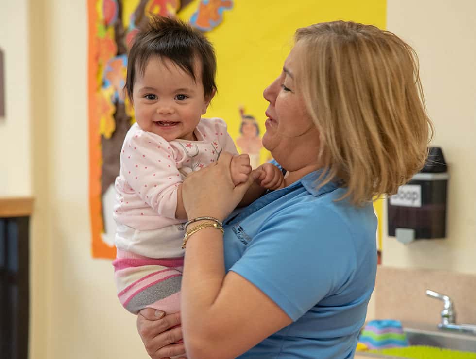 A baby smiling while being held by an adult