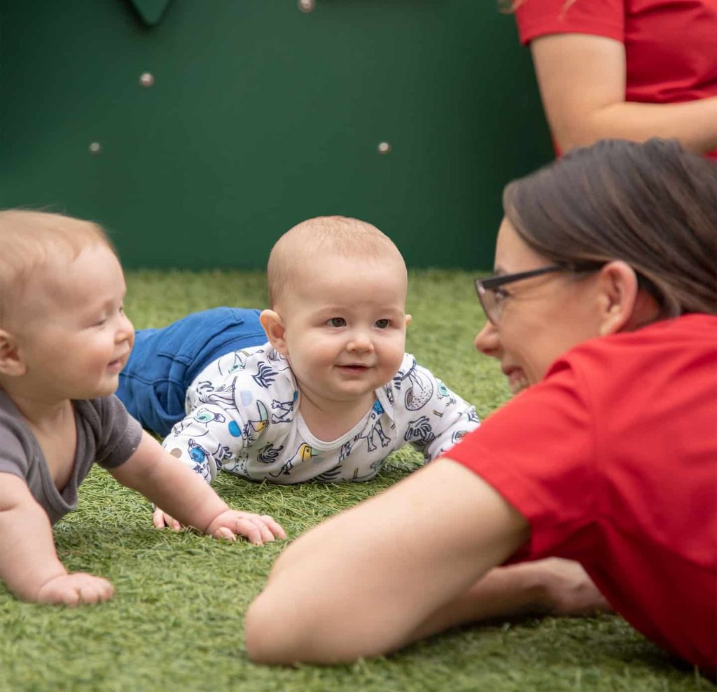 Babies smiling while lying on grass outdoors